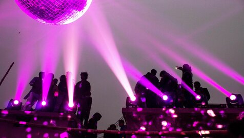 People standing on stage with purple lights scopio 3696eba1 053d 4b77 94b6 29fa43c44ca6